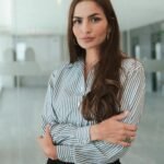 Professional woman with brown hair in a modern office, exuding confidence and poise.